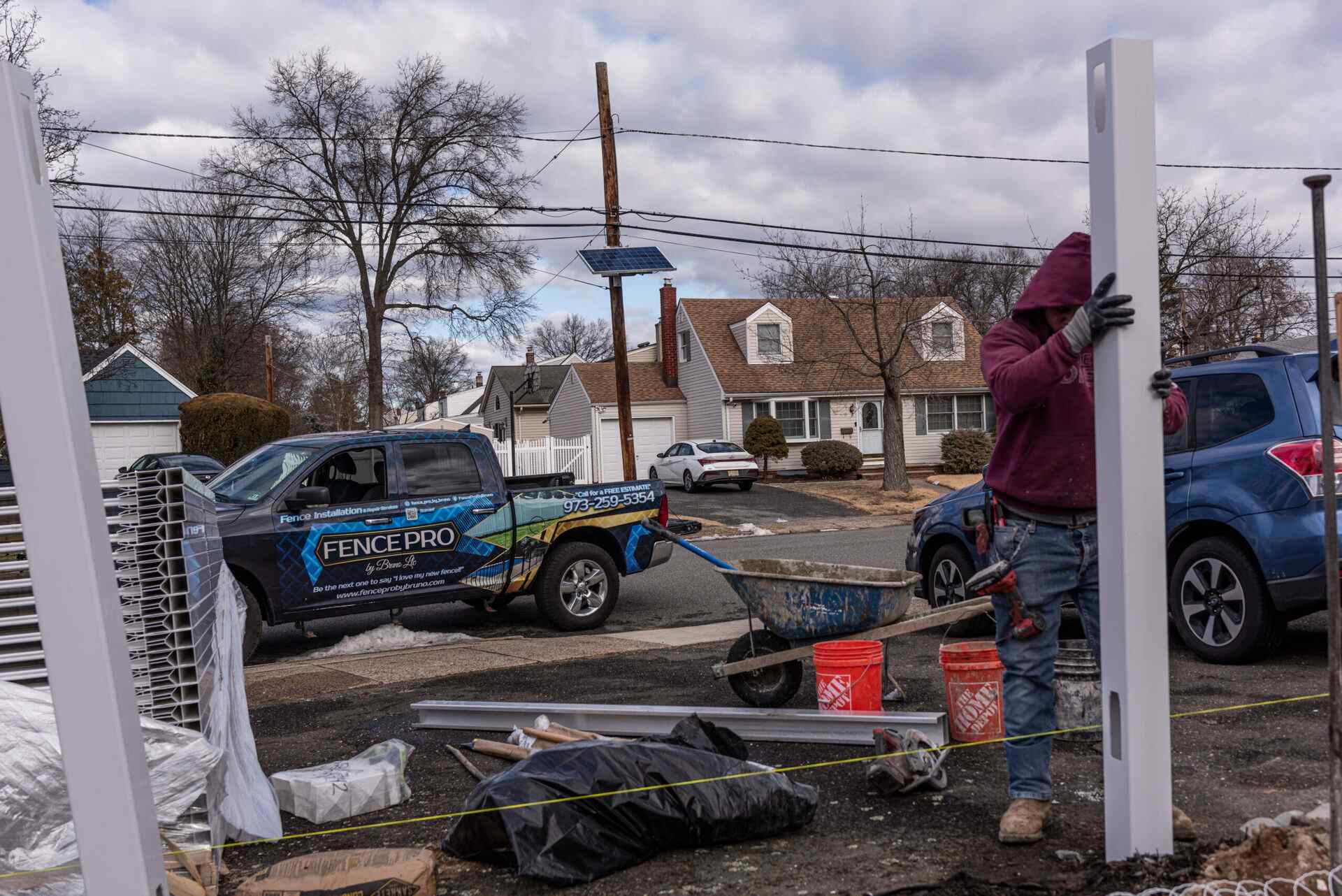 Fence Pro by Bruno installer raising a vinyl panel with the company truck behind